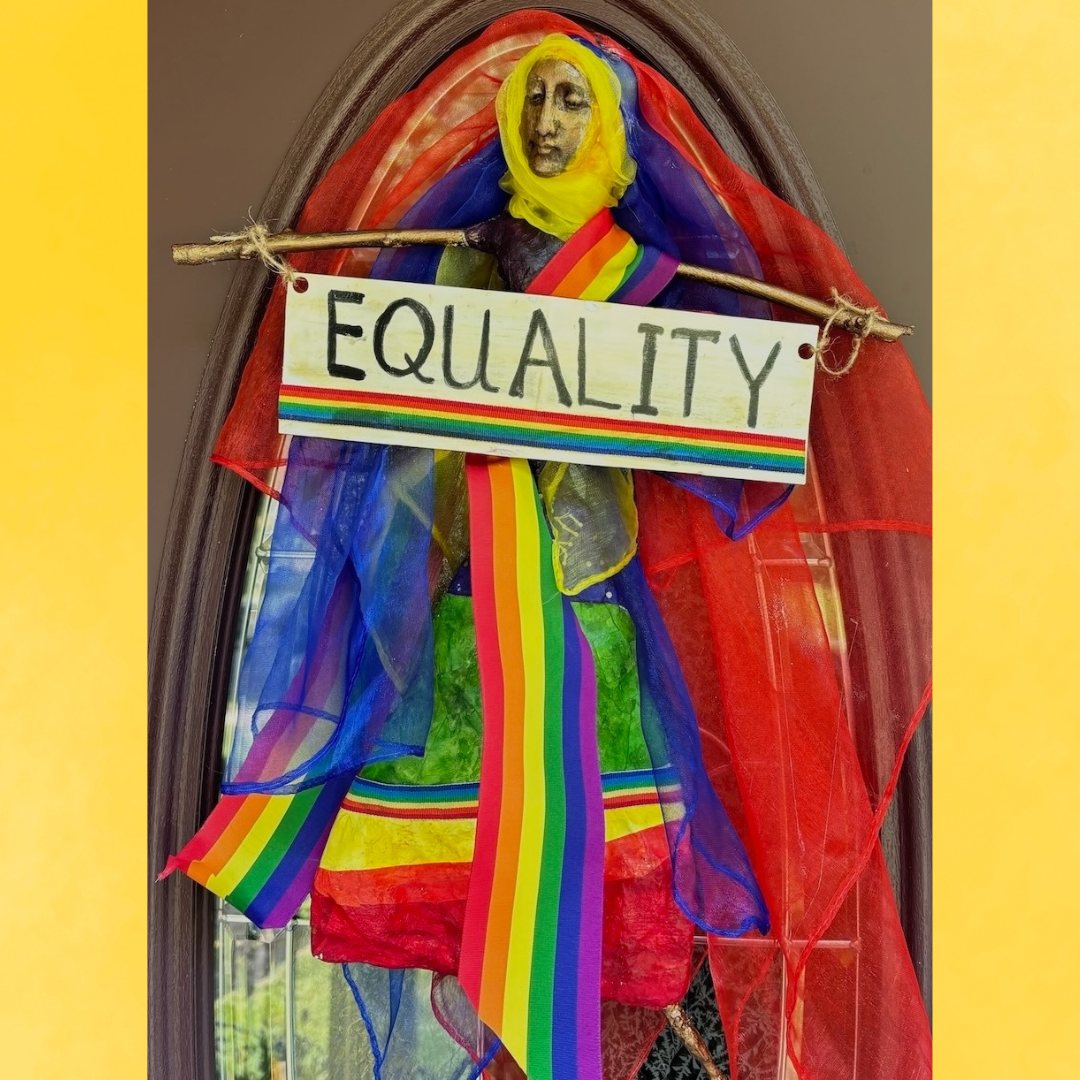 doll for hanging on wall or door that says equality, wearing pride flag colored colothes