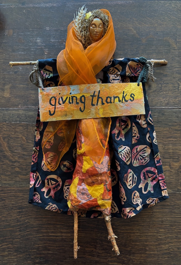 doll made of sticks and plaster with sign saying giving thanks